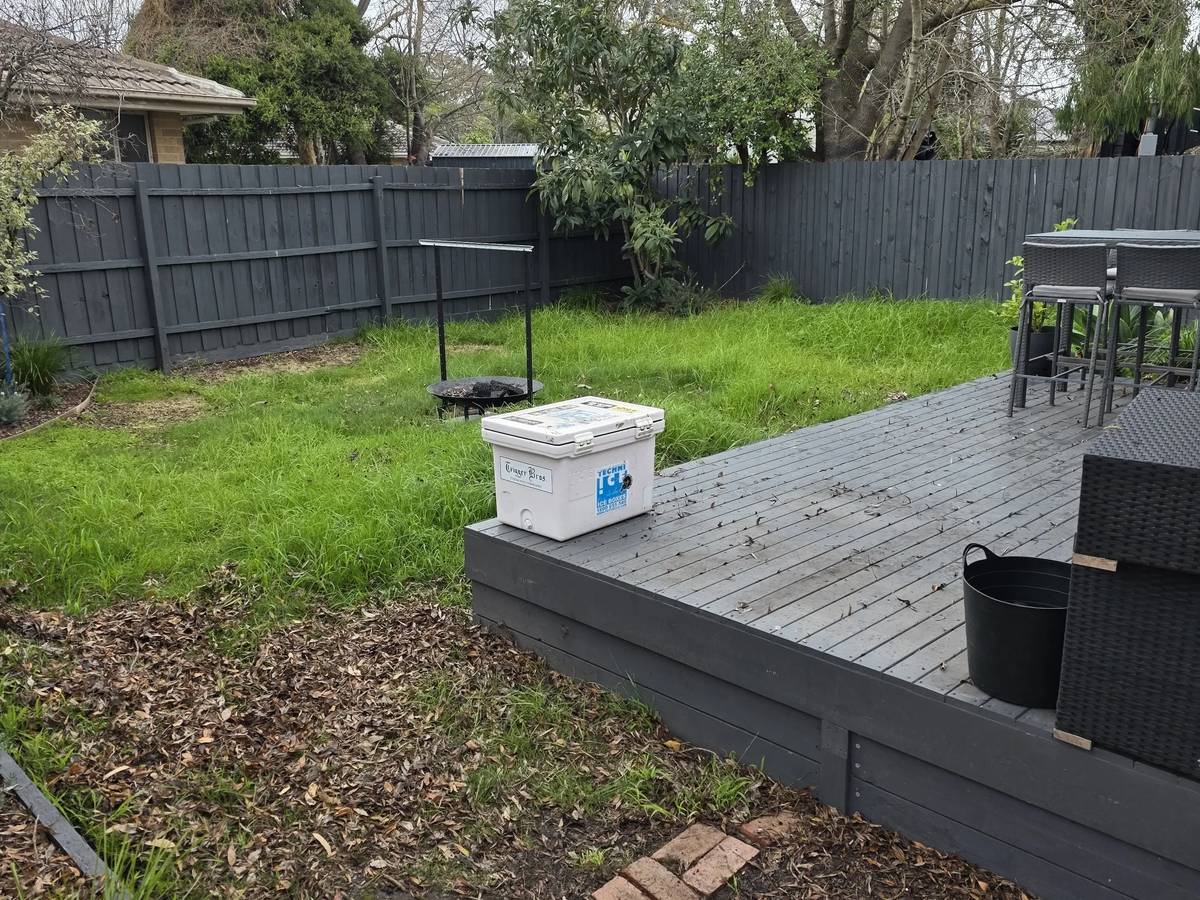 Patchy, overgrown back lawn around a timber deck before a Prestige Property Care visit