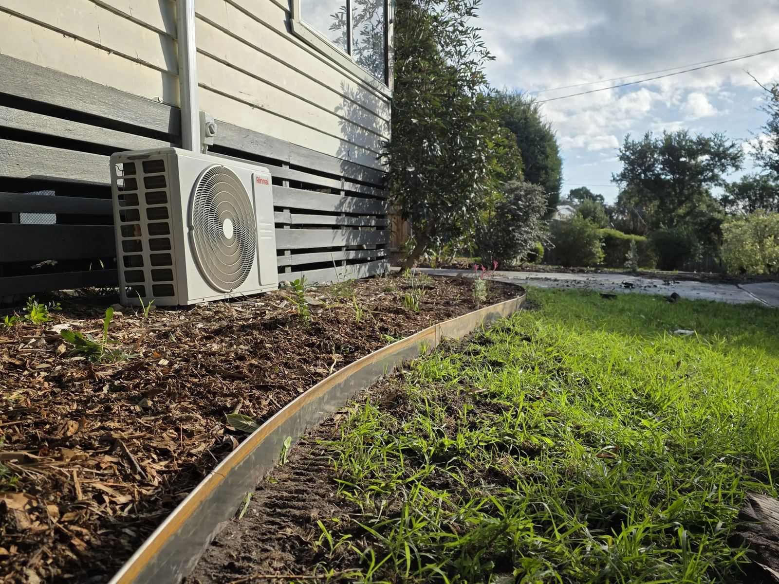 Garden bed remulched and re-edged beside a mown lawn during a regular garden maintenance visit in Frankston